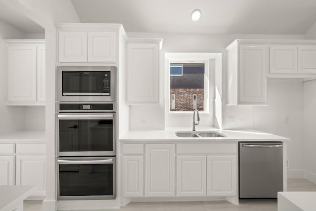 kitchen with stainless steel appliances, white cabinetry, and sink