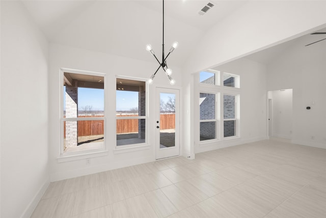 empty room with a healthy amount of sunlight, high vaulted ceiling, and a notable chandelier