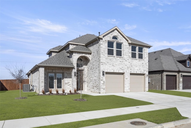 view of front of house with central AC unit, a garage, and a front lawn