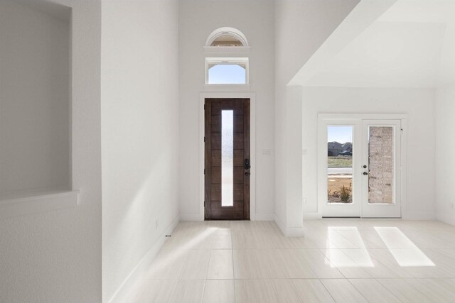 tiled foyer entrance with french doors and a high ceiling