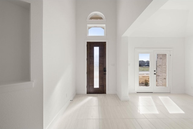 entrance foyer featuring a high ceiling, light tile patterned floors, and french doors