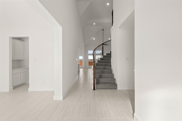 staircase featuring tile patterned flooring and high vaulted ceiling