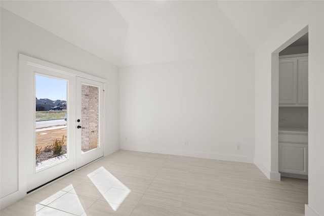 empty room featuring french doors, lofted ceiling, and light tile patterned floors