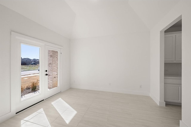 spare room with french doors, lofted ceiling, and light tile patterned floors