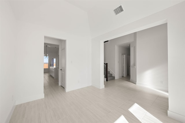 empty room featuring a towering ceiling and a notable chandelier