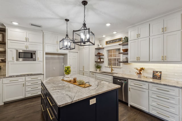 kitchen with white cabinets, stainless steel appliances, sink, and decorative light fixtures