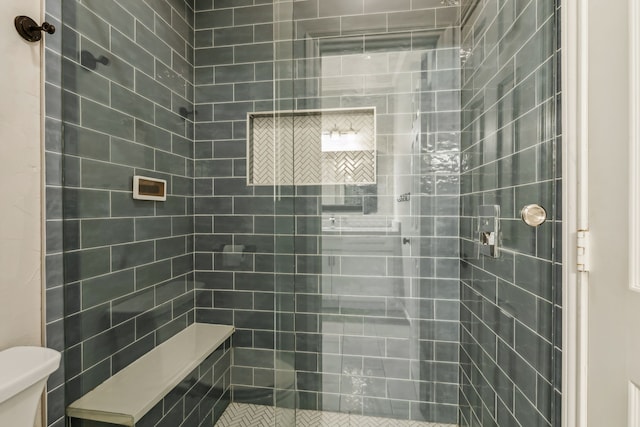 bathroom with a tile shower and toilet