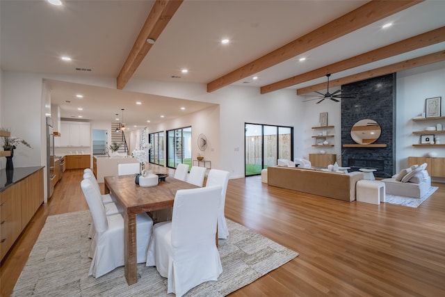 dining area featuring a fireplace, light hardwood / wood-style floors, ceiling fan, and beam ceiling