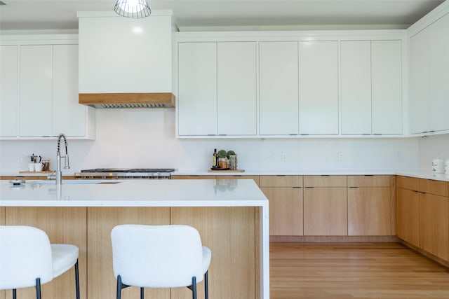 kitchen with white cabinets, a kitchen breakfast bar, and light hardwood / wood-style floors