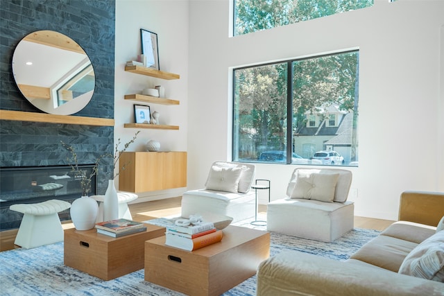 living room with wood-type flooring, a large fireplace, and a towering ceiling