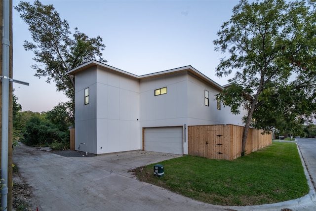 property exterior at dusk featuring a lawn and a garage