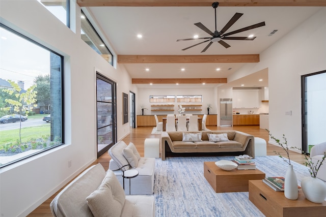 living room with ceiling fan, light hardwood / wood-style floors, and beamed ceiling