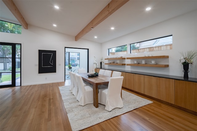 dining space with a skylight, light wood-type flooring, beam ceiling, and high vaulted ceiling