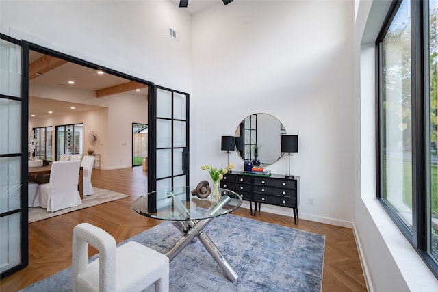 office area with parquet flooring, a high ceiling, a wealth of natural light, and beamed ceiling