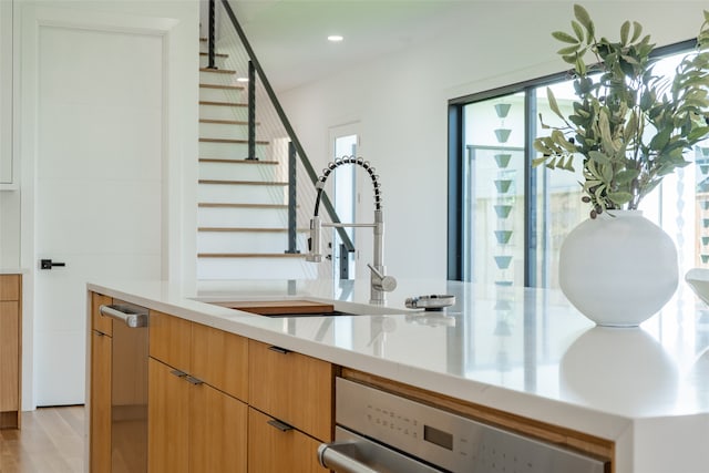 bar with sink, stainless steel dishwasher, and light hardwood / wood-style floors