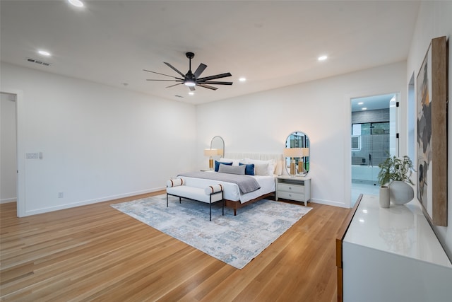 bedroom with ensuite bathroom, ceiling fan, and light hardwood / wood-style flooring