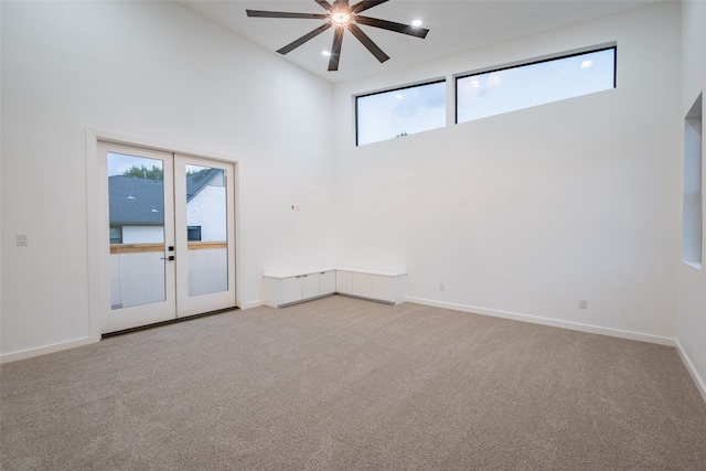 carpeted spare room with french doors, a high ceiling, and a wealth of natural light