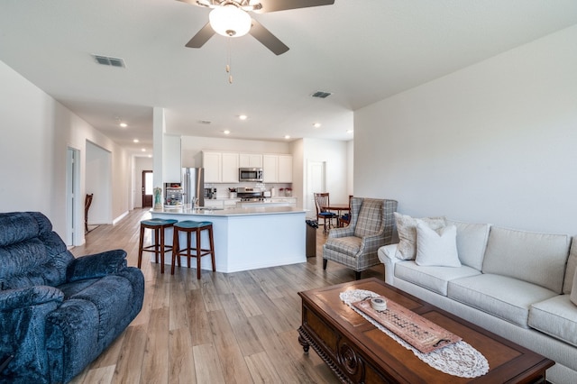 living room featuring ceiling fan and light hardwood / wood-style floors