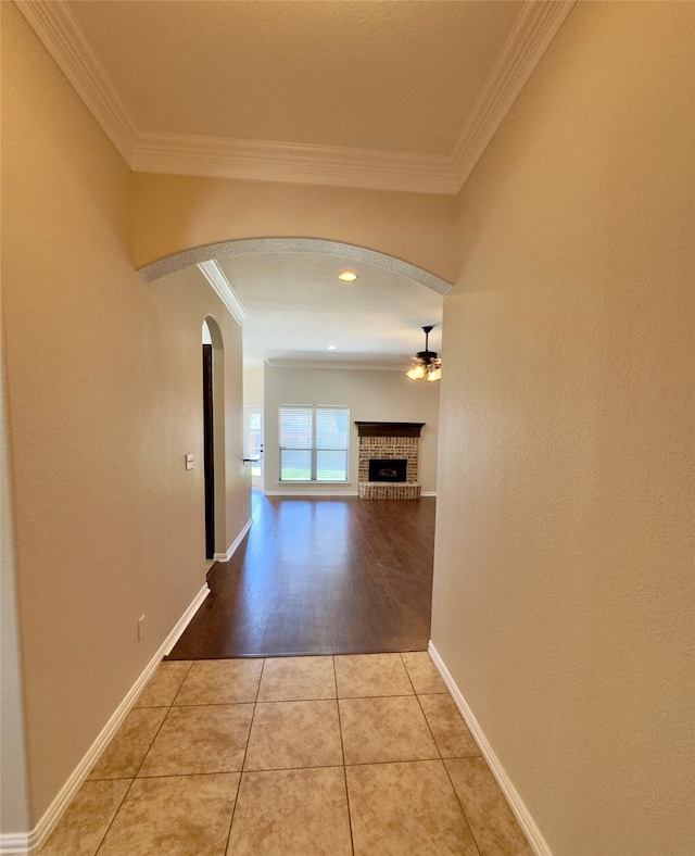 corridor with light wood-type flooring and ornamental molding