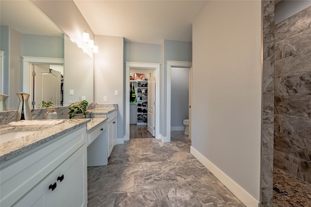 bathroom featuring tiled shower, vanity, and toilet