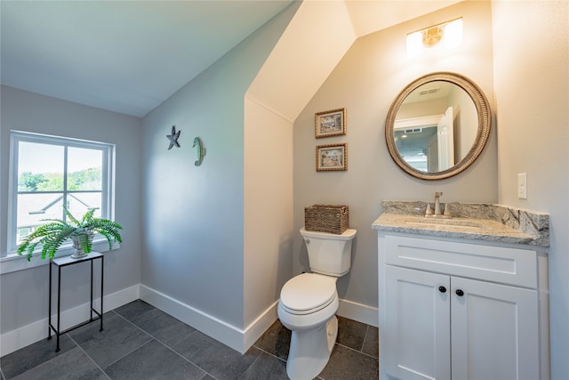 bathroom featuring tile patterned flooring, vaulted ceiling, vanity, and toilet