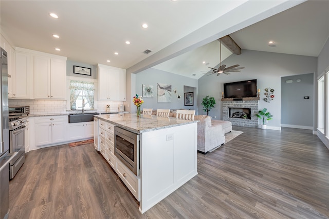 kitchen with appliances with stainless steel finishes, a fireplace, sink, and white cabinets