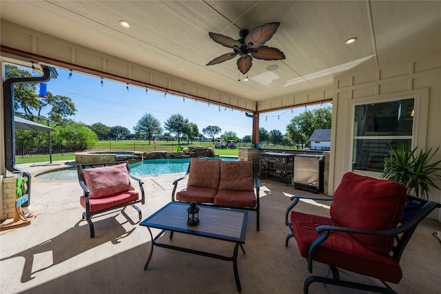 view of patio featuring ceiling fan, a swimming pool with hot tub, and an outdoor kitchen