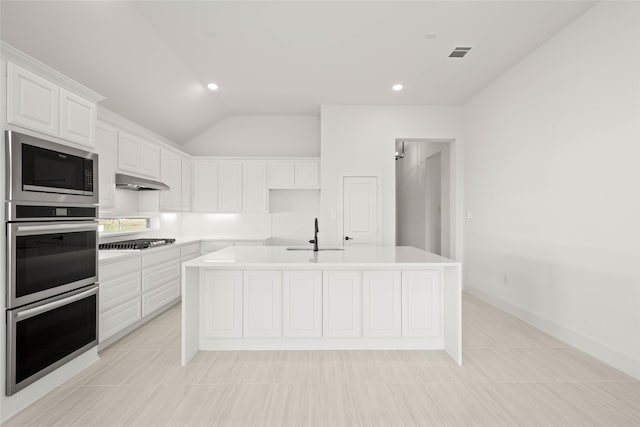 kitchen with lofted ceiling, sink, appliances with stainless steel finishes, an island with sink, and white cabinets