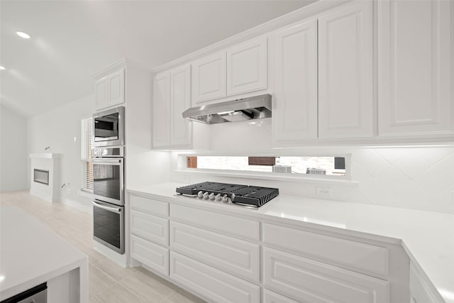 kitchen featuring stainless steel appliances, extractor fan, decorative backsplash, and white cabinets