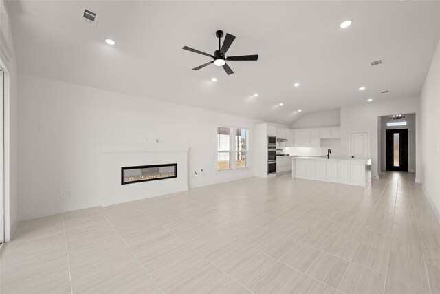 unfurnished living room featuring sink, vaulted ceiling, and ceiling fan