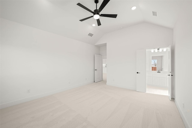 unfurnished bedroom with light colored carpet, lofted ceiling, and connected bathroom