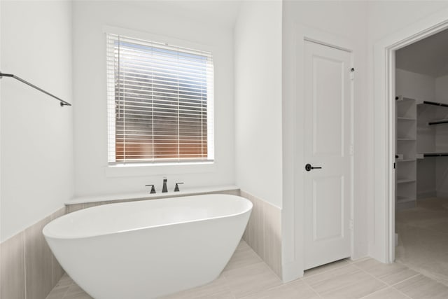 bathroom featuring tile patterned flooring, tile walls, and a bathtub