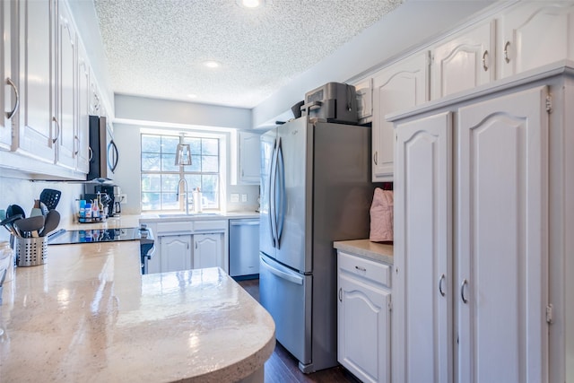 kitchen featuring white cabinetry, kitchen peninsula, appliances with stainless steel finishes, a textured ceiling, and sink