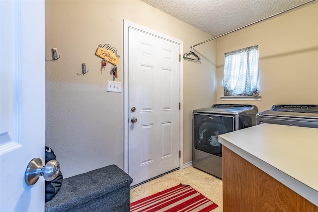 laundry area featuring washing machine and clothes dryer and a textured ceiling