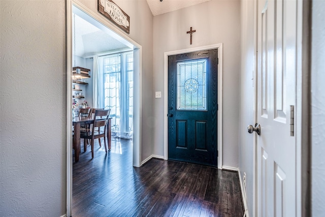 entryway featuring vaulted ceiling, dark hardwood / wood-style flooring, and a textured ceiling