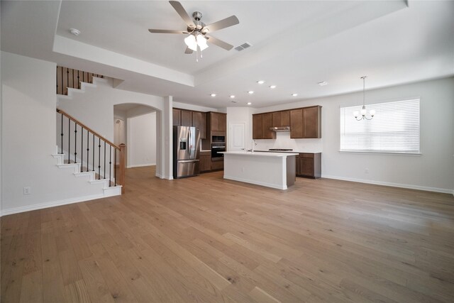 interior space featuring light wood finished floors, visible vents, stairs, a tray ceiling, and recessed lighting