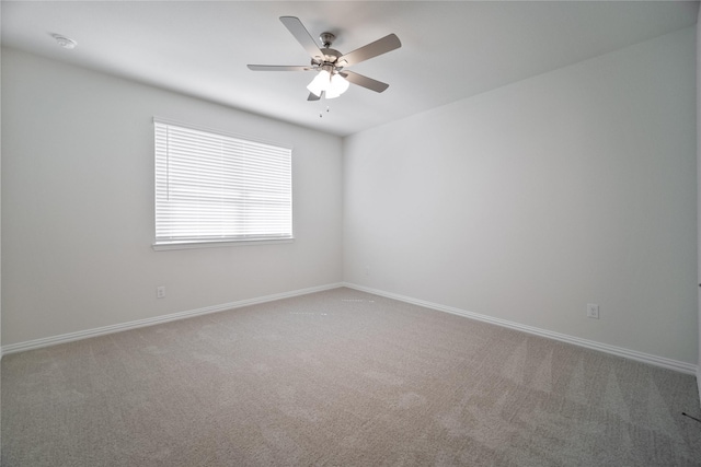 carpeted spare room with ceiling fan and baseboards