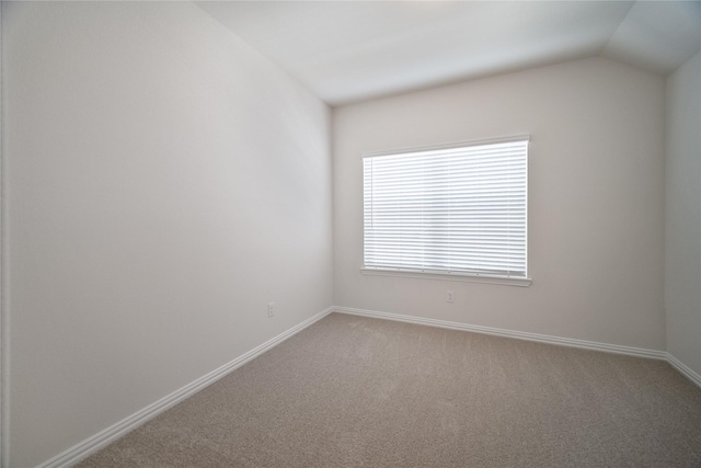 empty room featuring lofted ceiling, light carpet, and baseboards