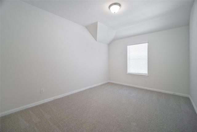 empty room featuring lofted ceiling, baseboards, and carpet flooring