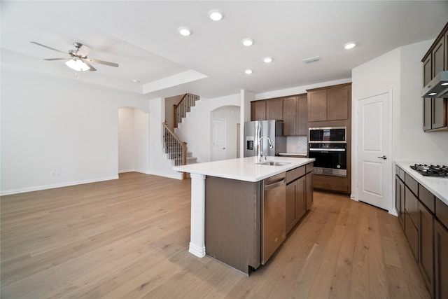 kitchen with arched walkways, visible vents, light wood-style flooring, appliances with stainless steel finishes, and a sink