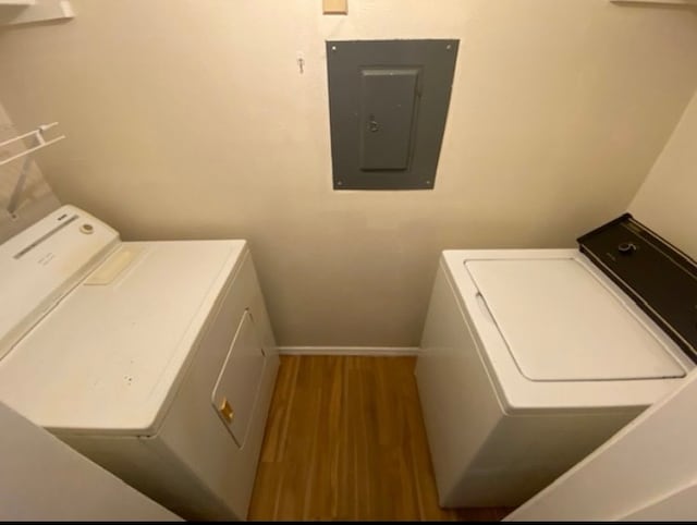 laundry area featuring hardwood / wood-style flooring, electric panel, and washing machine and dryer