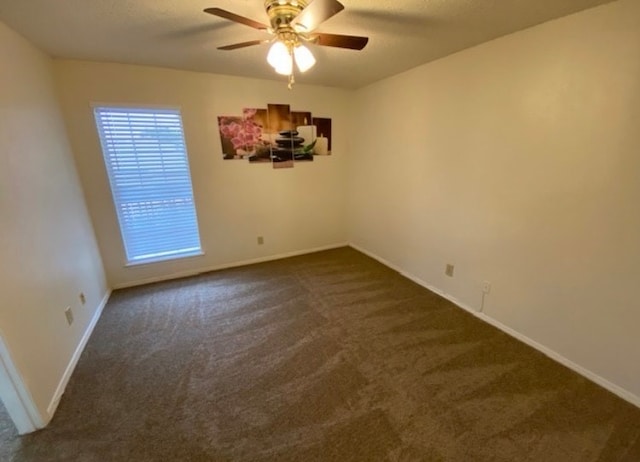 unfurnished room with dark carpet and ceiling fan