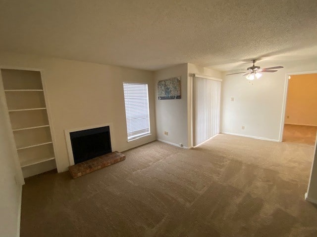 unfurnished living room with a textured ceiling, a fireplace, carpet flooring, and ceiling fan