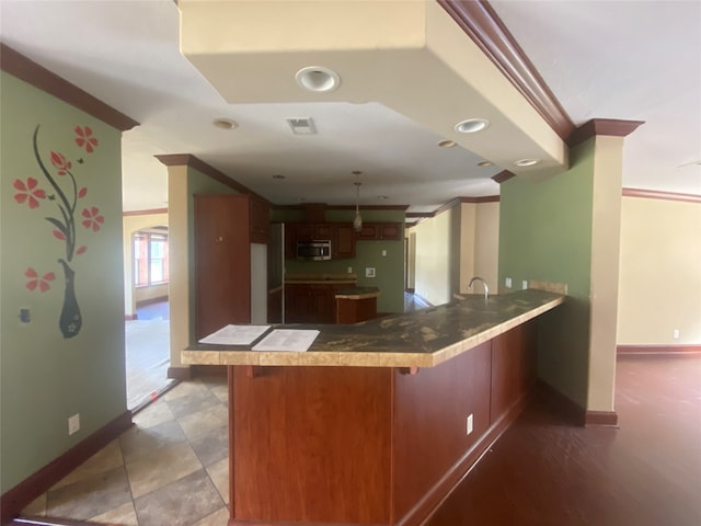 kitchen featuring a breakfast bar area, crown molding, kitchen peninsula, and sink