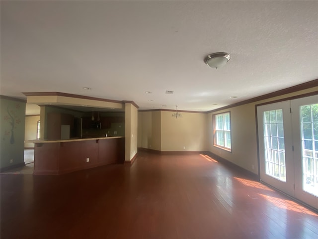 unfurnished living room featuring ornamental molding, a textured ceiling, and dark hardwood / wood-style flooring