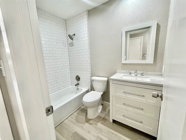 full bathroom with tiled shower / bath combo, vanity, toilet, and hardwood / wood-style flooring