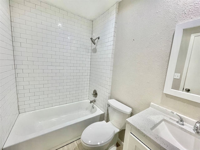 full bathroom featuring tiled shower / bath, vanity, and toilet