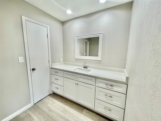 bathroom with wood-type flooring, a textured ceiling, and vanity