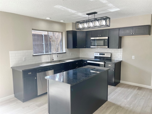 kitchen featuring light hardwood / wood-style floors, a textured ceiling, hanging light fixtures, a kitchen island, and stainless steel appliances