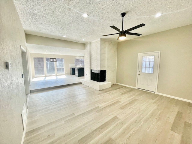 unfurnished living room with light hardwood / wood-style floors, a wealth of natural light, ceiling fan, and a brick fireplace